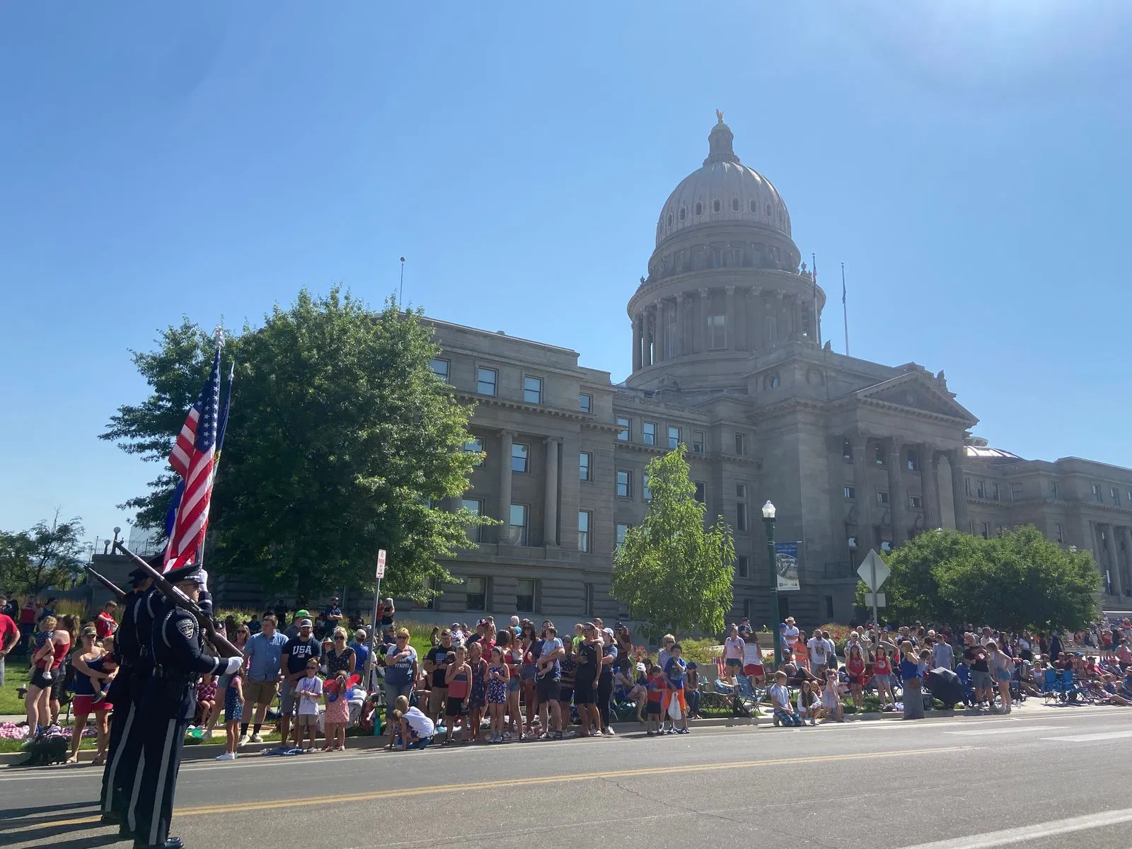 Crowd of people watching the honor guard in the Boise 4th of July Independence Day Parade in front of the Boise capitol building.